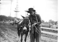 [Unidentified rodeo clown standing by his mule]
