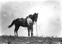 [Unidentified cowgirl standing beside horse]