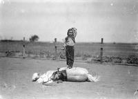 [Little Girl, Jean Graham, standing on the side of pony which is laying on its side]