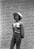 [Unidentified cowgirl posed in front of brick wall]