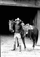 [Col. Jim Eskew stands with horse in front of barn entrance]