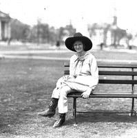 [Unidentified cowgirl on park bench in park]