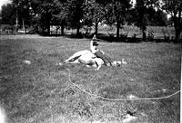 [Sumner Hixon spinning rope loop above himself while he lies on his pony which is also reclining]