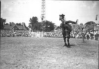 [Frank Finley riding and staying with his bronc "Ginger" in front of stands]