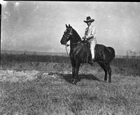 [Possibly Jack Hughes in large hat and light-colored outfit on horse with tassels on head]