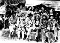 [Eleven cowgirls and two little girls posed on hay bales]