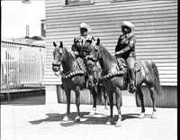 [Unidentified Cowgirl and Cowboy with roses on shirts on two matched horses]