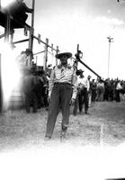 [Single unidentified cowboy standing in front of chutes with initials "JS" on tie]