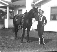 [Unidentified lady trick rider standing by horse]