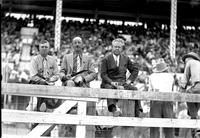 [Ray Talbot sitting behind fence with two unidentified business-suited men]