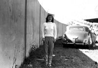 [Unidentified woman in western hat posed by fence]