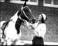 [Unidentified woman standing beside horse]