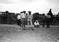 [Possibly Everett Colborn stands beside unidentified man in necktie & cowboy hat in front of chutes]