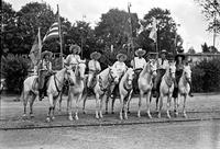 [Mamie Francis & California Frank on horses amid three mounted cowgirls and two mounted cowboys]