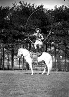 [Possibly Junior Eskew standing on horse spinning a vertical rope loop in front of himself]