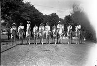 [Mamie Francis & California Frank on horses amid five mounted cowgirls and three mounted cowboys]