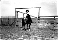 [Possibly Tillie Bowman with rope on saddle in front of corral]