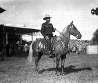 [Possibly Fred Beeson in dark shirt with white piping on horse with silver mounted bit & bridle]