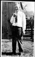 [Will Rogers standing in front of stable wearing a necktie]