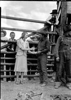 [Unidentified Woman in formal attire presenting buckle & shaking hands with unidentified cowboy]