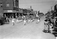 [Majorettes lead Teague High School Marching Band down city street followed by others]