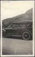 [3 women sitting in an automobile on a highway, near a mountain]