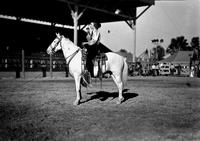 [Unidentified cowgirl on horse using microphone in arena]