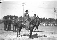 [Unidentified cowboy holding rope while mounted on horse]