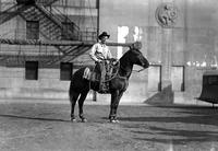 [Unidentified cowboy atop stationary horse and holding rope loop with both hands at his side]
