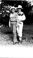 [Unidentified cowgirl and elderly cowboy standing together]