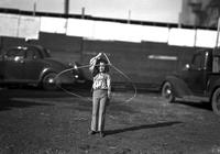 [Young unidentified cowgirl spinning a rope loop around herself]