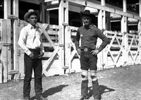 [Two unidentified cowboys standing in front of chutes, one with knees wrapped in ace bandages]