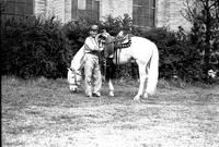 [Bob Wills wearing U.S. Army uniform standing by white horse wearing silver saddle]