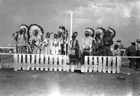 [Group of ten Indian men and women on platform behind fence]