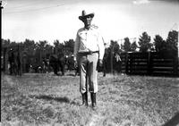 [Single unidentified cowboy standing in front of corral]