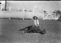 [Little cowgirl sitting on side of lying pony]