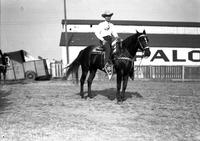 [Possibly Johnnie Lee Wills on dark horse wearing silver mounted saddle. Trailer in background]