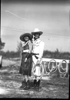 [Unidentified cowgirl & cowboy standing together near ropes]