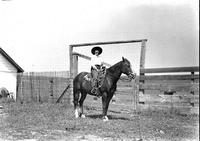 [Possibly Tillie Bowman with rope on saddle in front of corral]