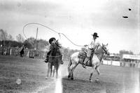 [Unidentified Cowboy atop stationary horse and roping a passing cowboy atop a moving horse]