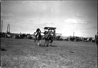 [Unidentified Cowboy sitting on stationary horse roping passing rider]