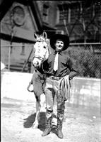 [Possibly Junior Eskew with tie, rope in hand and flower pattern on boots standing with horse]