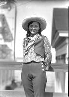 [Unidentified cowgirl leaning against rail]