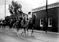 [Pair of unidentified cowgirls on horseback moving down trolley car tracks]