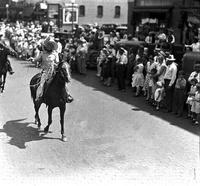 [Unidentified Cowboy throwing rope with loop up in air atop horse; crowd looks on]