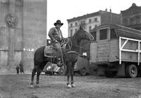 [Unidentified cowboy posed on horse with end of horse trailer behind]