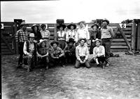 [Group of cowboys and cowgirls including Sally Rand Greenough & Leo Cremer in front of chutes]
