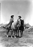 [Unidentified Cowgirl and Cowboy atop horses, side by side hand]
