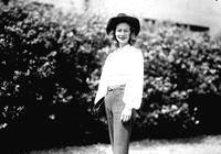 [Unidentified cowgirl in front of bushes]