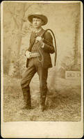 Man posing in a nature scene with whip and cartridge belt
